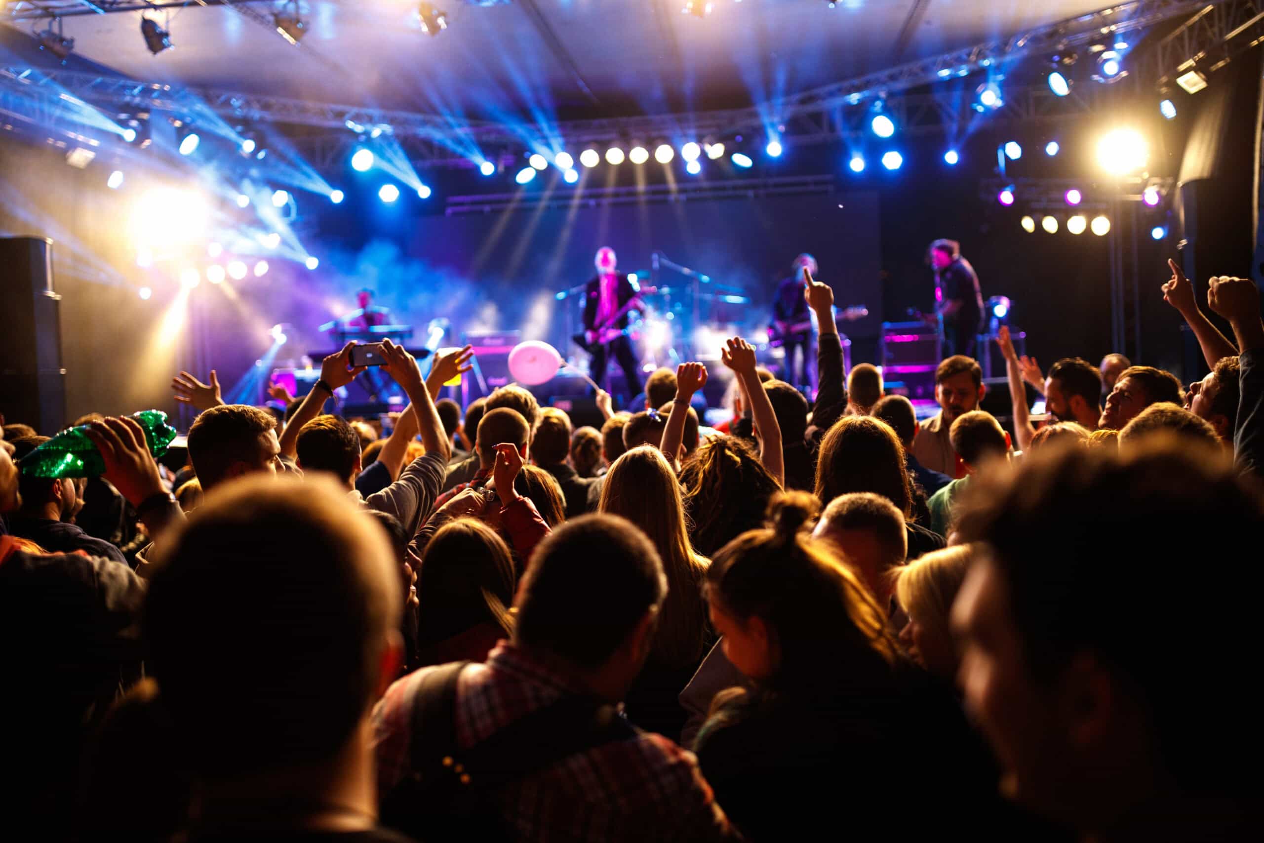 Crowd watching a live band performing on stage at a music event.
